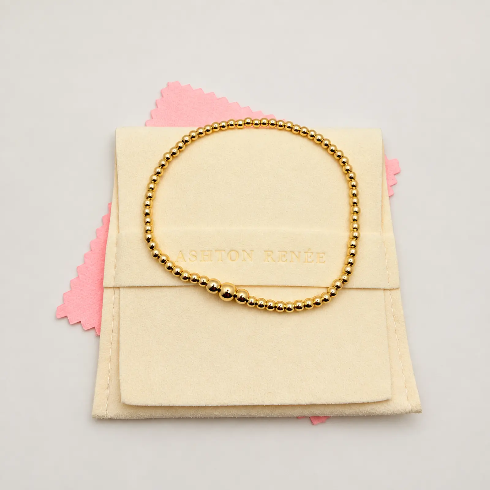 The Ashton bracelet displayed on a cream ASHTON RENÉE jewelry pouch with a pink polishing cloth