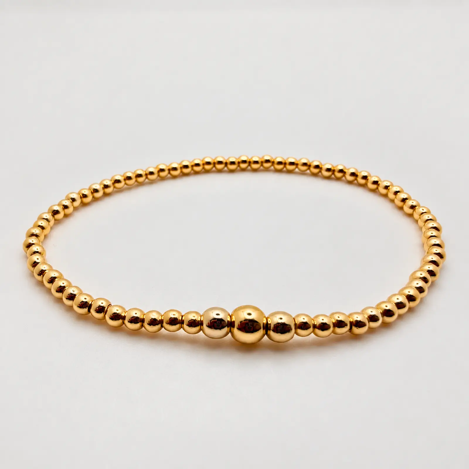 The Ashton stretch bracelet arranged in a circle, handcrafted with polished 14K gold-filled beads in graduated sizes