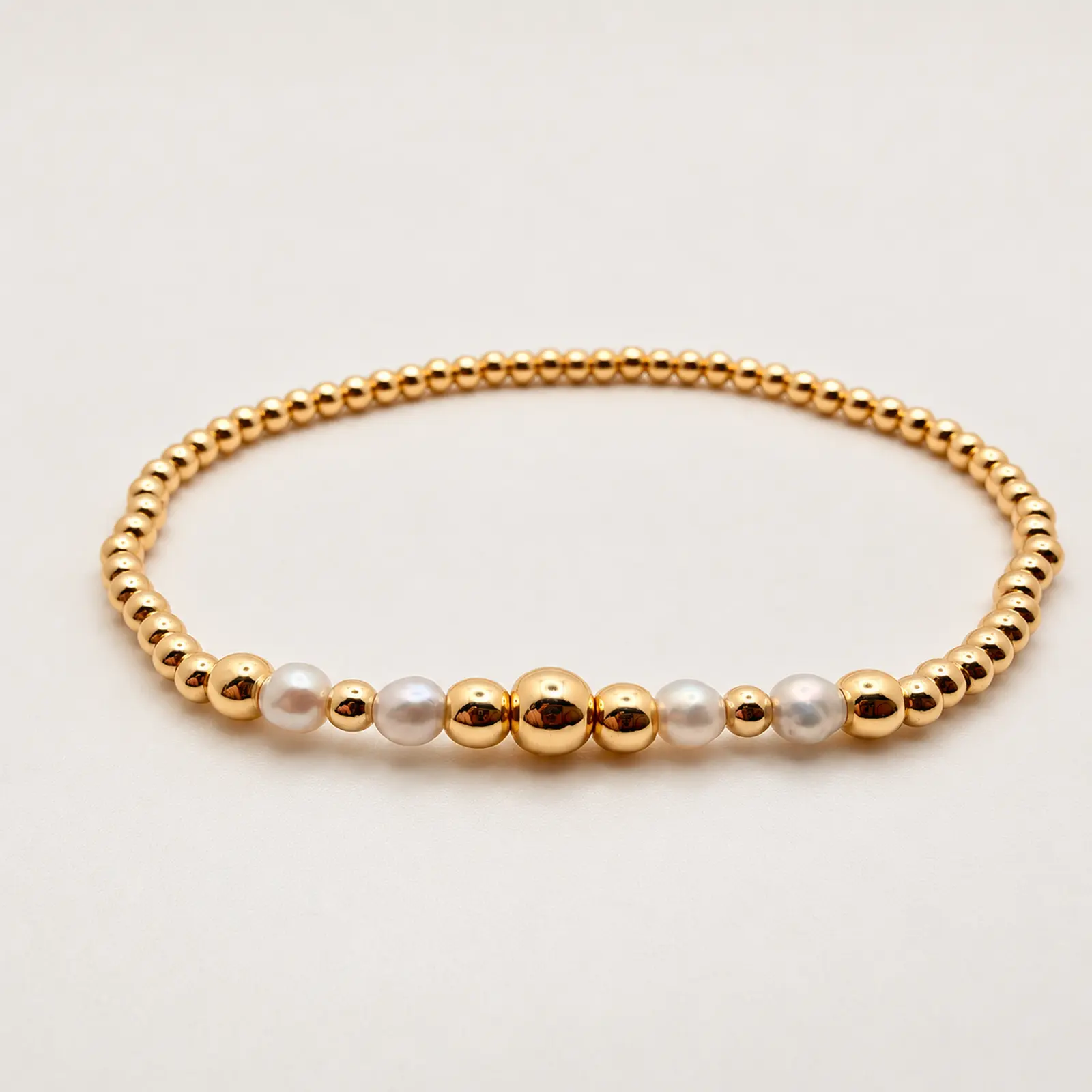 The Melissa stretch bracelet arranged in a circle, with four freshwater pearls and polished 14K gold-filled beads